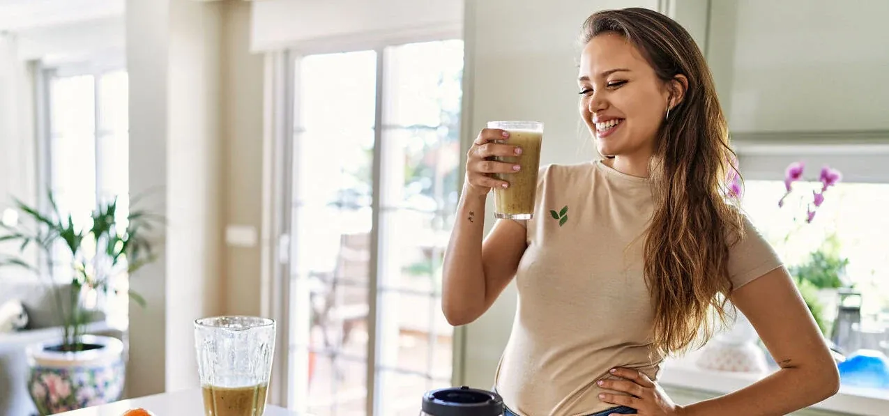 A woman in a UK kitchen holding a freshly blended Herbalife shake